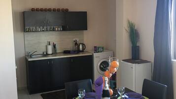 Una cocina compacta con armarios oscuros, una lavadora y un refrigerador pequeño.