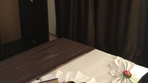 A hotel room with a bed, a wooden dresser, and a mirror.