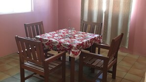 Un comedor con una mesa cubierta por un mantel estampado, rodeado de sillas de madera.