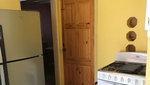 Una cocina con refrigerador, horno y puerta de madera.