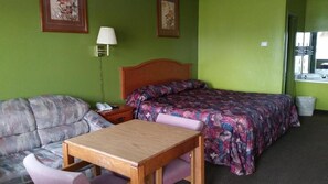 A room with a bed, a sofa, a table, and a lamp. - Parkview Motel (Corning)