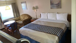 A hotel room with a bed, a chair, a desk, and a lamp. - Parkview Motel (Corning)