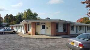A single-story motel with a central entrance, a covered parking area, and a car parked in front. - Medina Inn (Medina)