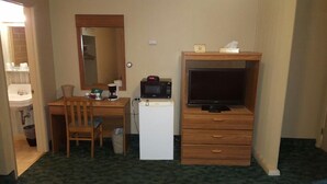 A compact room with a wooden desk, a small refrigerator, a microwave, a television, and a mirror. - Medina Inn (Medina)
