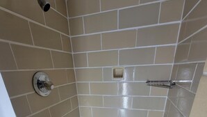 A small, tiled shower with a drain in the center, a showerhead on the left, and a towel rack on the right. - Medina Inn (Medina)