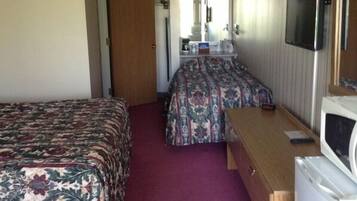 A compact hotel room with two beds, a desk, a television, and a microwave.