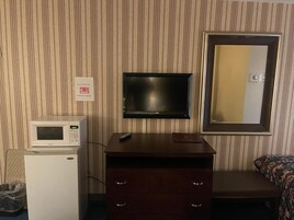 Quarto de hotel com micro-ondas, televisão, cómoda e espelho.