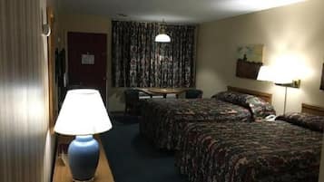 Ein Hotelzimmer mit zwei Betten, einem Schreibtisch, einem Stuhl, einer Lampe und einem Vorhang.