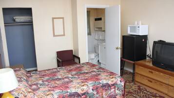 A hotel room with a bed, a desk, a chair, a wardrobe, a bathroom, and a television.