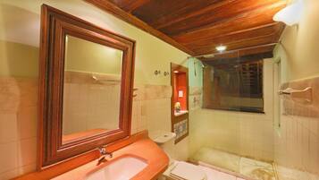 A bathroom with a wooden ceiling, a sink, a toilet, and a shower area.