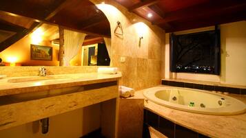 A bathroom with a wooden vanity, a bathtub, and a window with a view of the city at night.