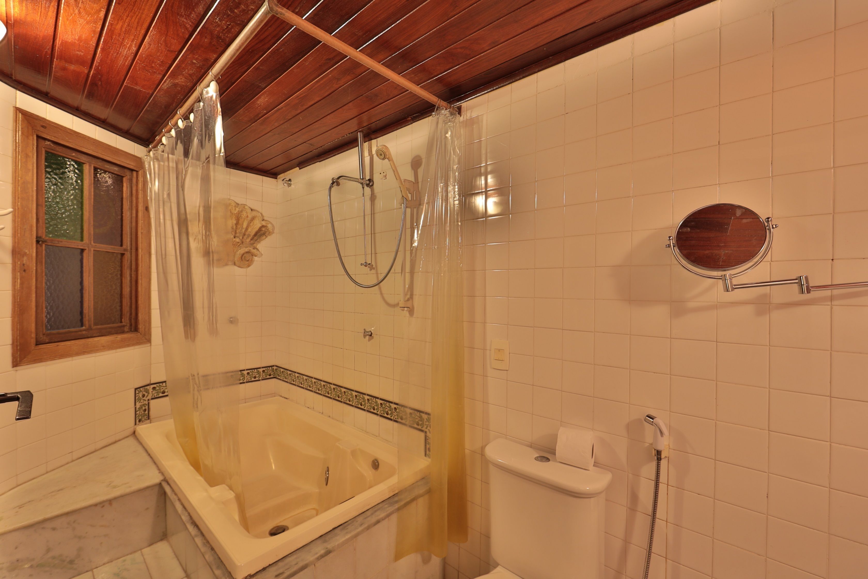 A bathroom with a bathtub, toilet, and shower area.
