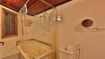 A bathroom with a bathtub, toilet, and shower area.
