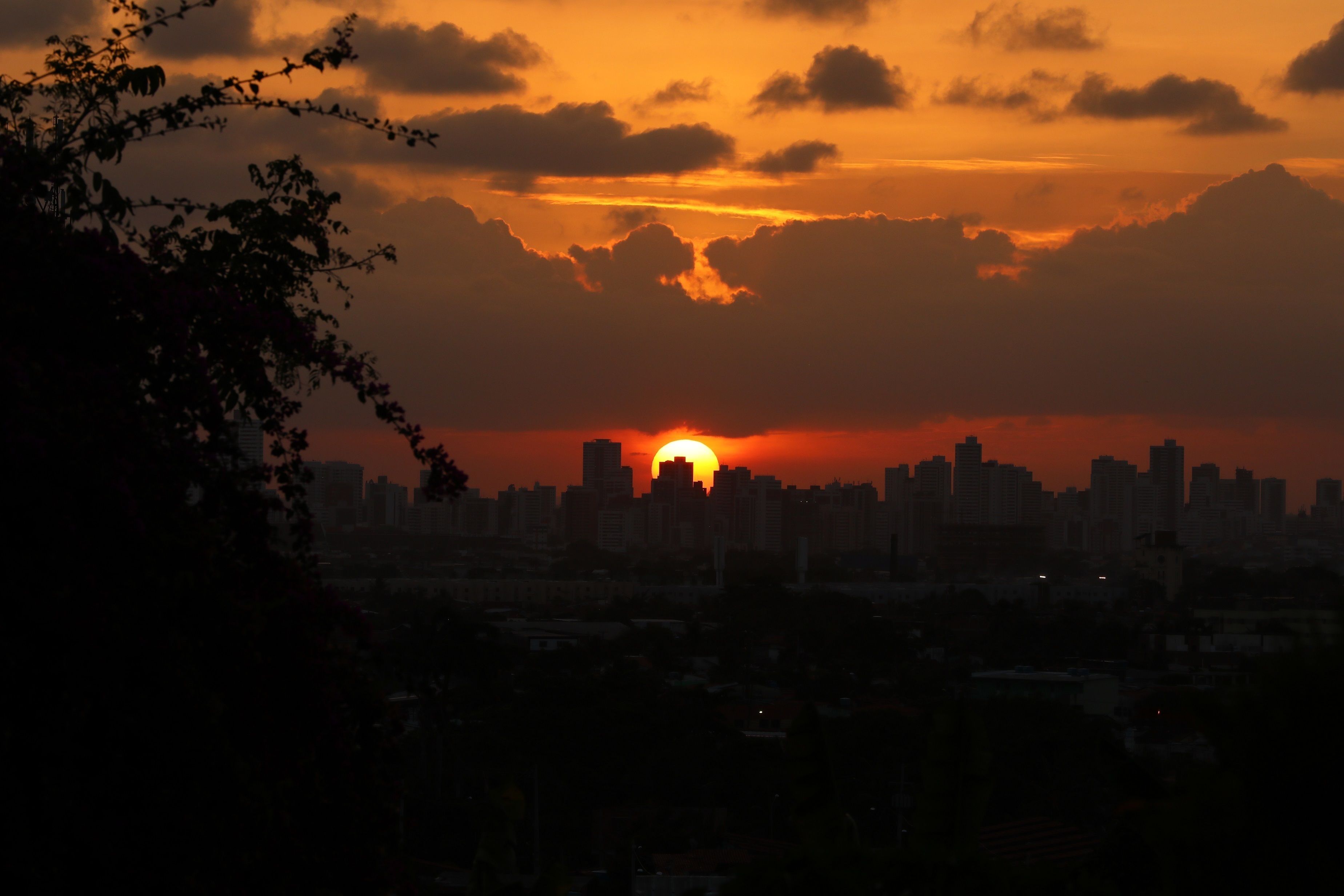 Une vue sur les gratte-ciel d’une ville au coucher du soleil, avec des nuages dans le ciel.
