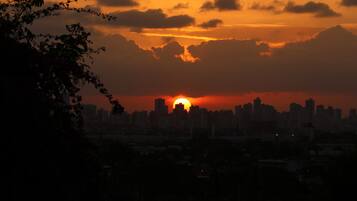Une vue sur les gratte-ciel d’une ville au coucher du soleil, avec des nuages dans le ciel.