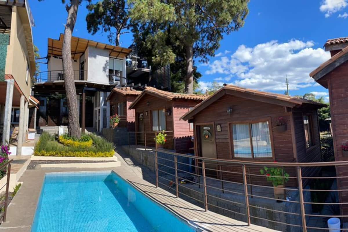 Una casa de madera con balcón, piscina y vista a la montaña.