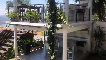 Un patio exterior cubierto con una pérgola, zona de estar y una chimenea.
