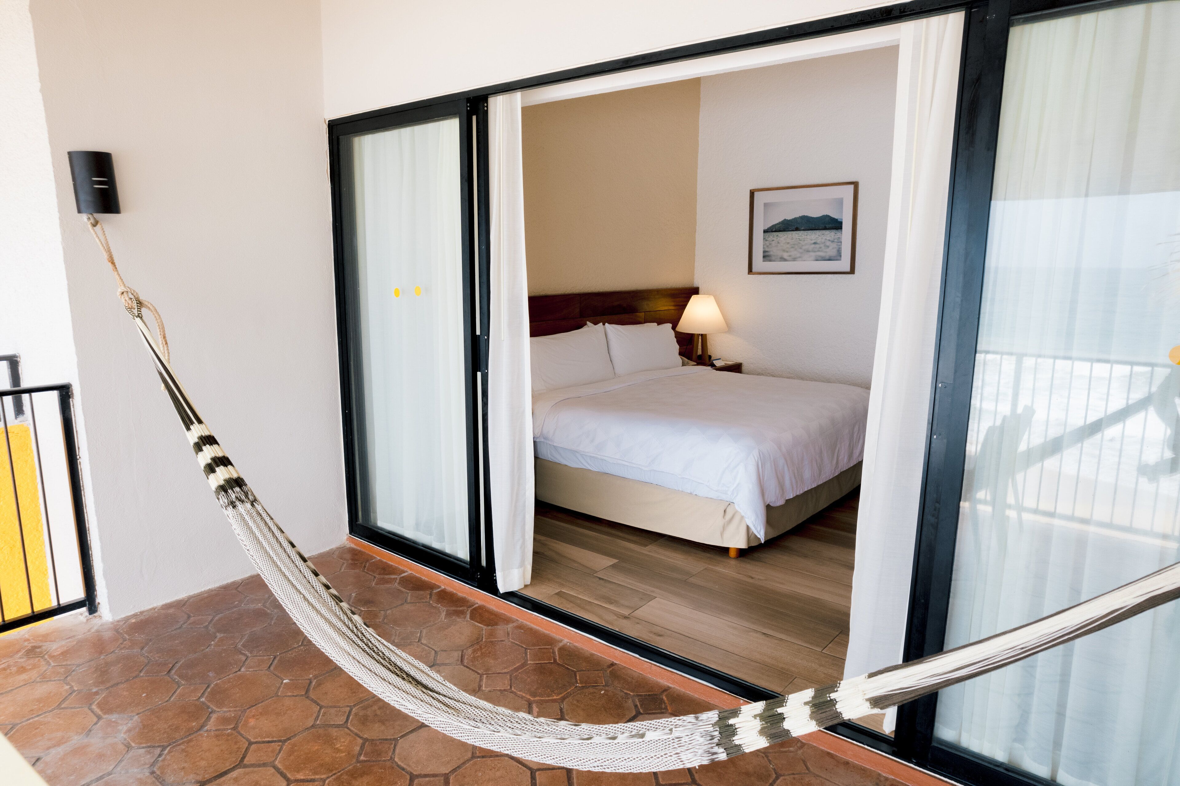 A room with a bed, a nightstand, a lamp, and a hammock.