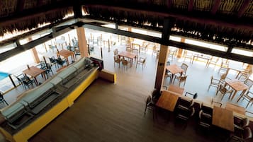 A spacious restaurant with high ceilings, wooden tables and chairs, and a central seating area with benches.
