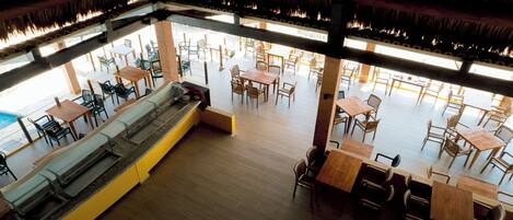 A spacious restaurant with high ceilings, wooden tables and chairs, and a central seating area with benches.