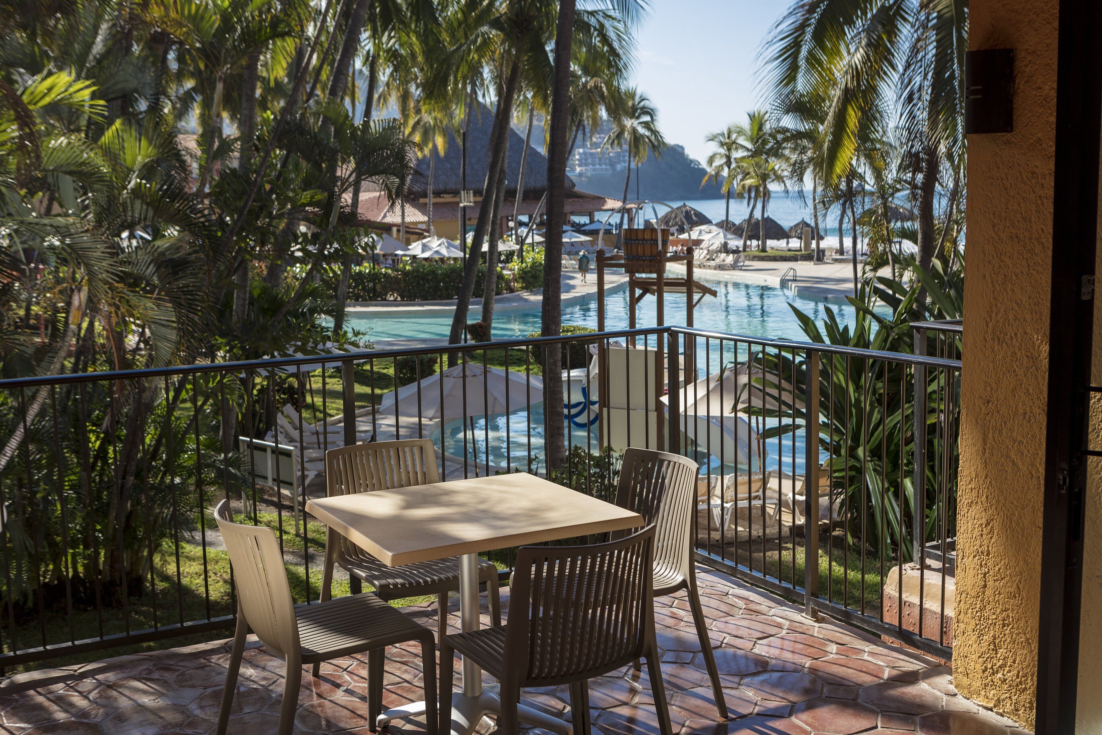 Eine Terrasse mit Pool, Stühlen und Tisch mit Blick auf Strand und Meer.