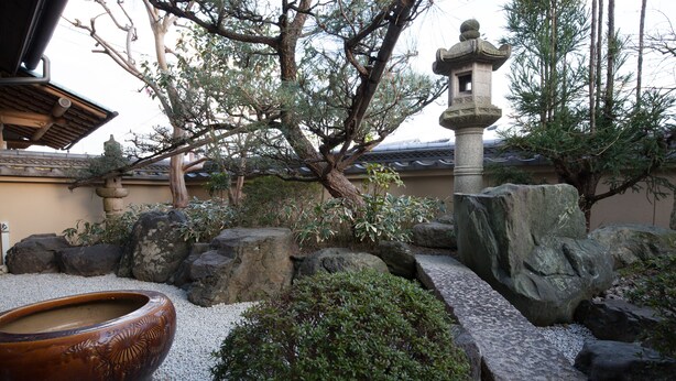 A traditional Japanese garden with a stone lantern, a large ceramic bowl, and various rocks and plants. - CHIKUYOAN (Nagaokakyo)