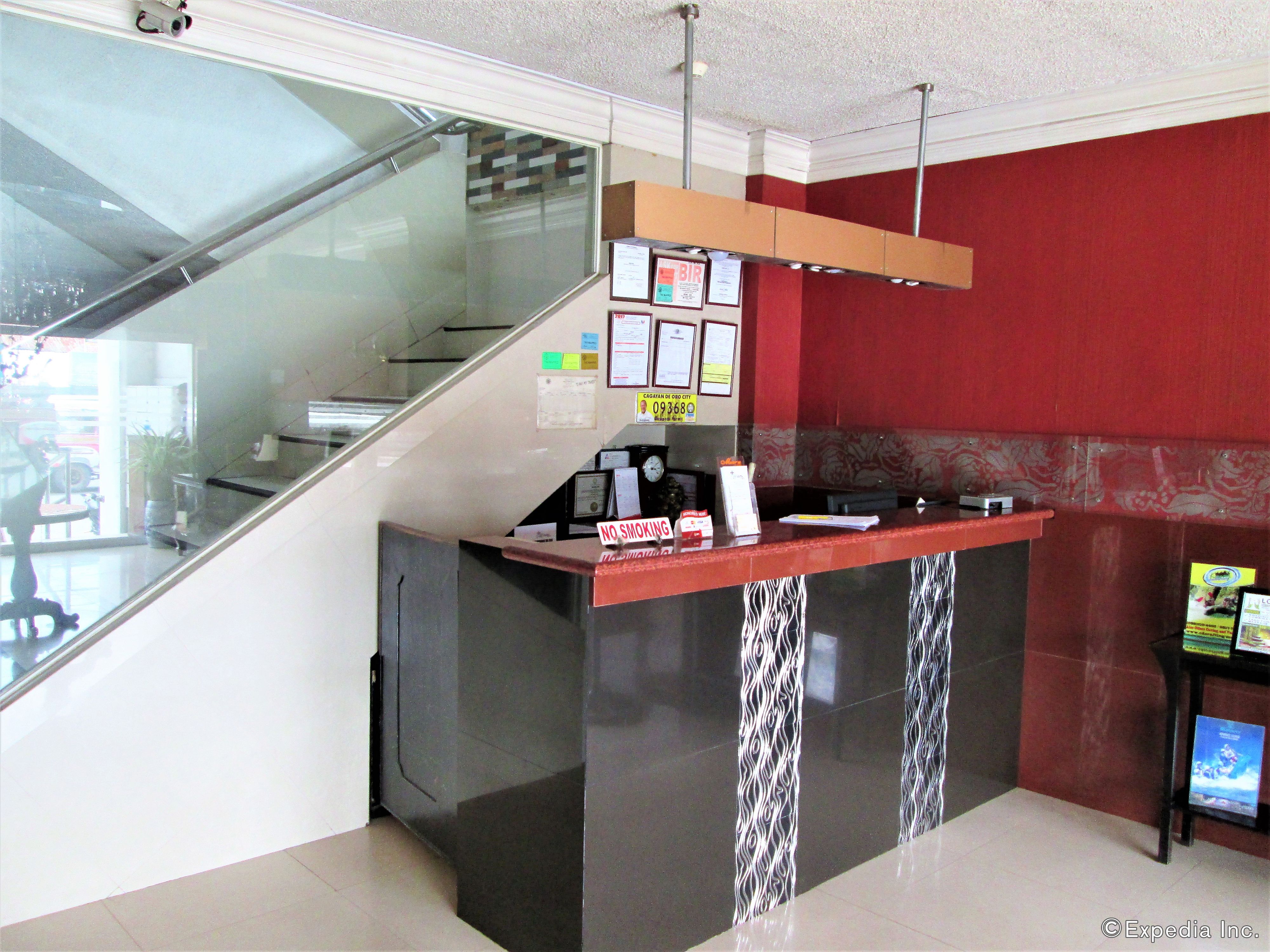 A reception desk with a glass partition, a clock, and various informational posters.