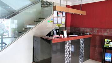 A reception desk with a glass partition, a clock, and various informational posters.