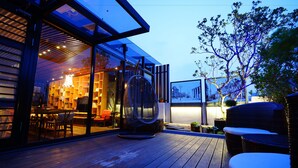 An outdoor wooden deck with a glass door leading to an interior dining area. - 3 Door Hotel (Tainan)