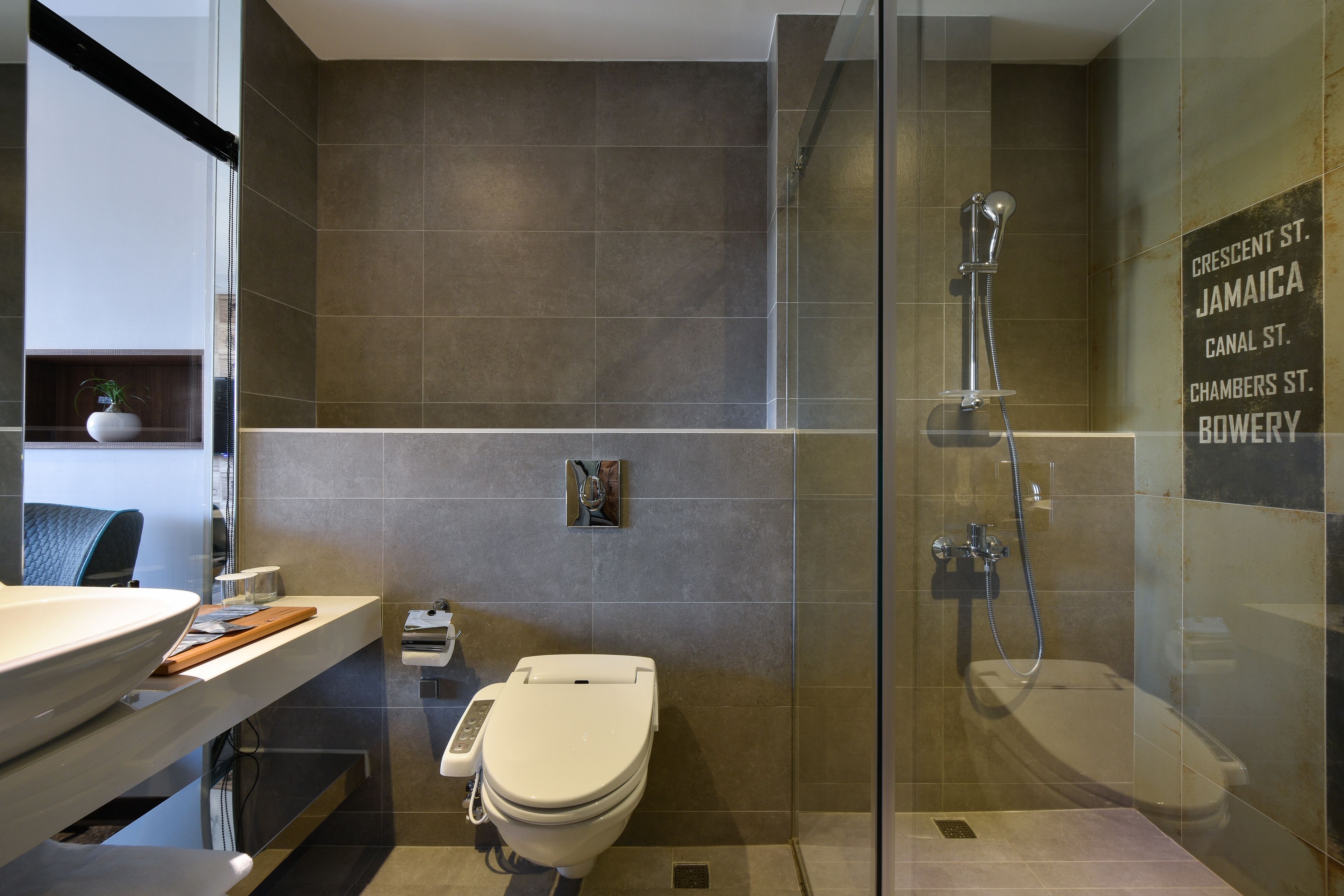 Un baño moderno con ducha de vidrio, inodoro y tocador con lavamanos.