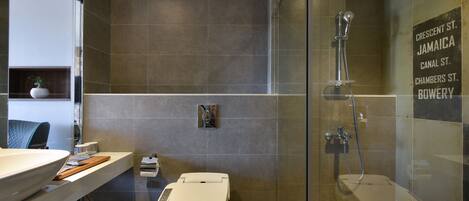 Un baño moderno con ducha de vidrio, inodoro y tocador con lavamanos.