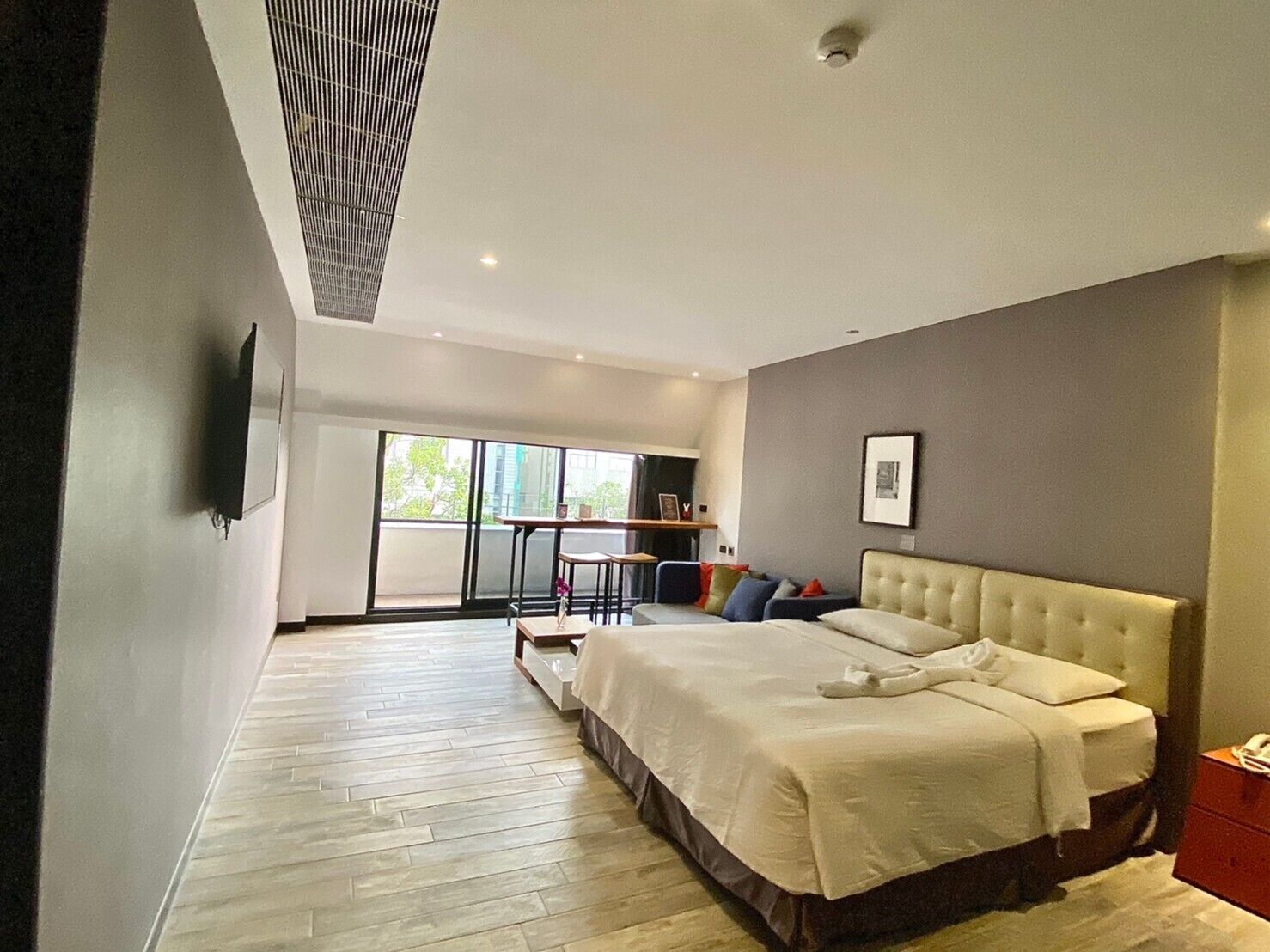 Una habitación de hotel moderna con una cama grande, una mesita y vistas al exterior.