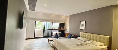 Una habitación de hotel moderna con una cama grande, una mesita y vistas al exterior.