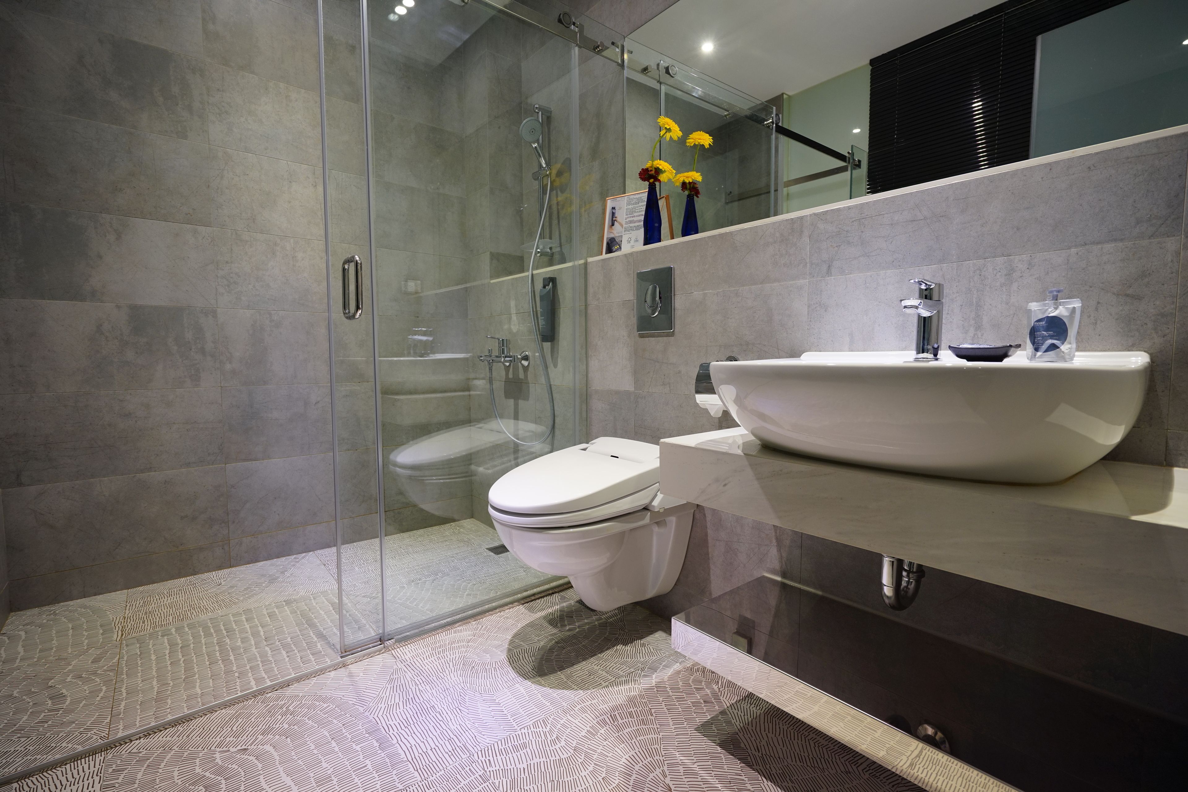 A modern bathroom with a glass-enclosed shower, a white toilet, and a vanity with a large sink.