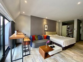Una habitación de hotel moderna con cama, sofá, mesa de centro de madera y un escritorio con silla.