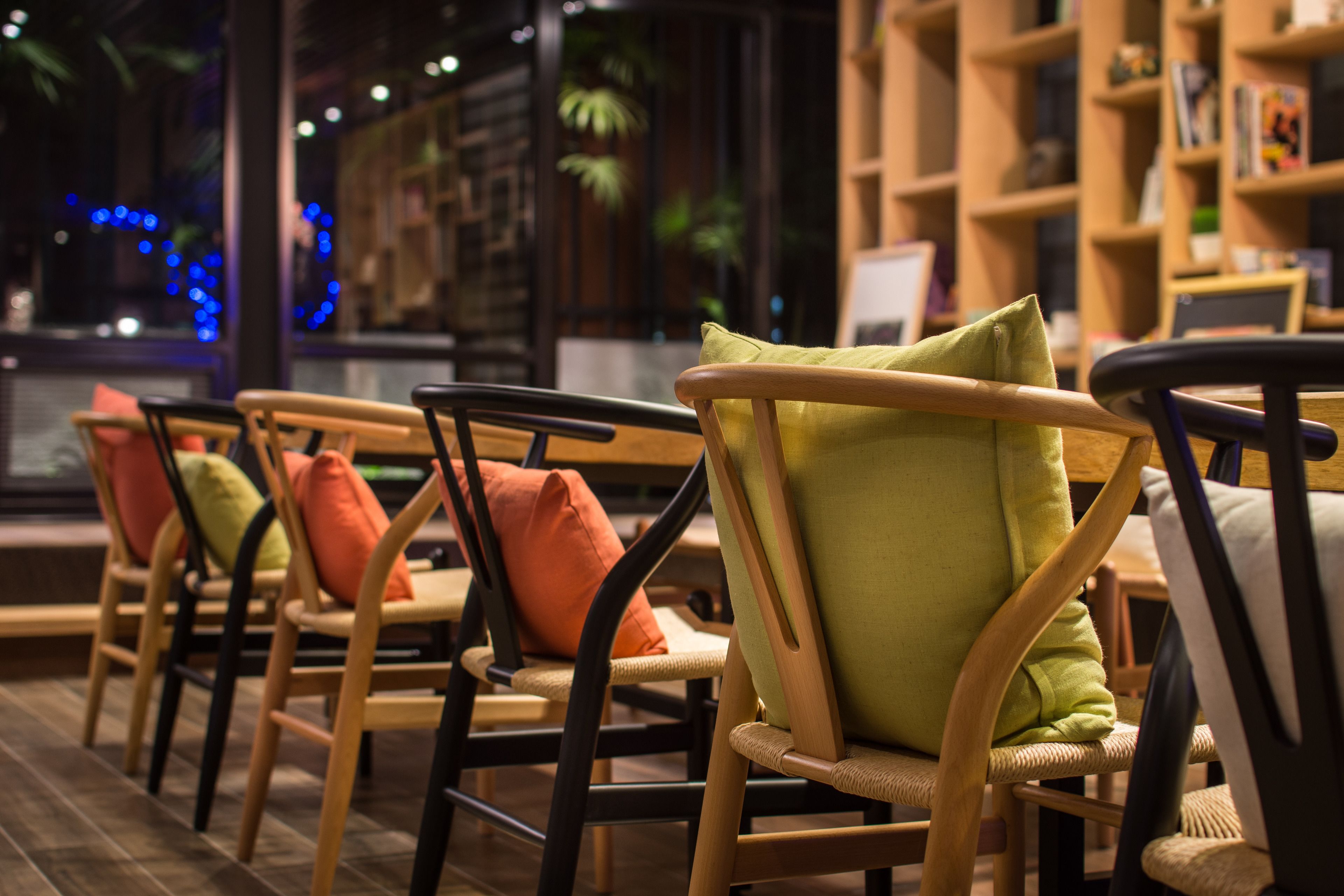 Une rangée de chaises en bois, dotées de coussins, disposées dans un espace intérieur accueillant, avec vue sur l’extérieur.