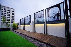 A modern outdoor area with a wooden deck, artificial grass, and framed pictures on a wall. - 3 Door Hotel (Tainan)