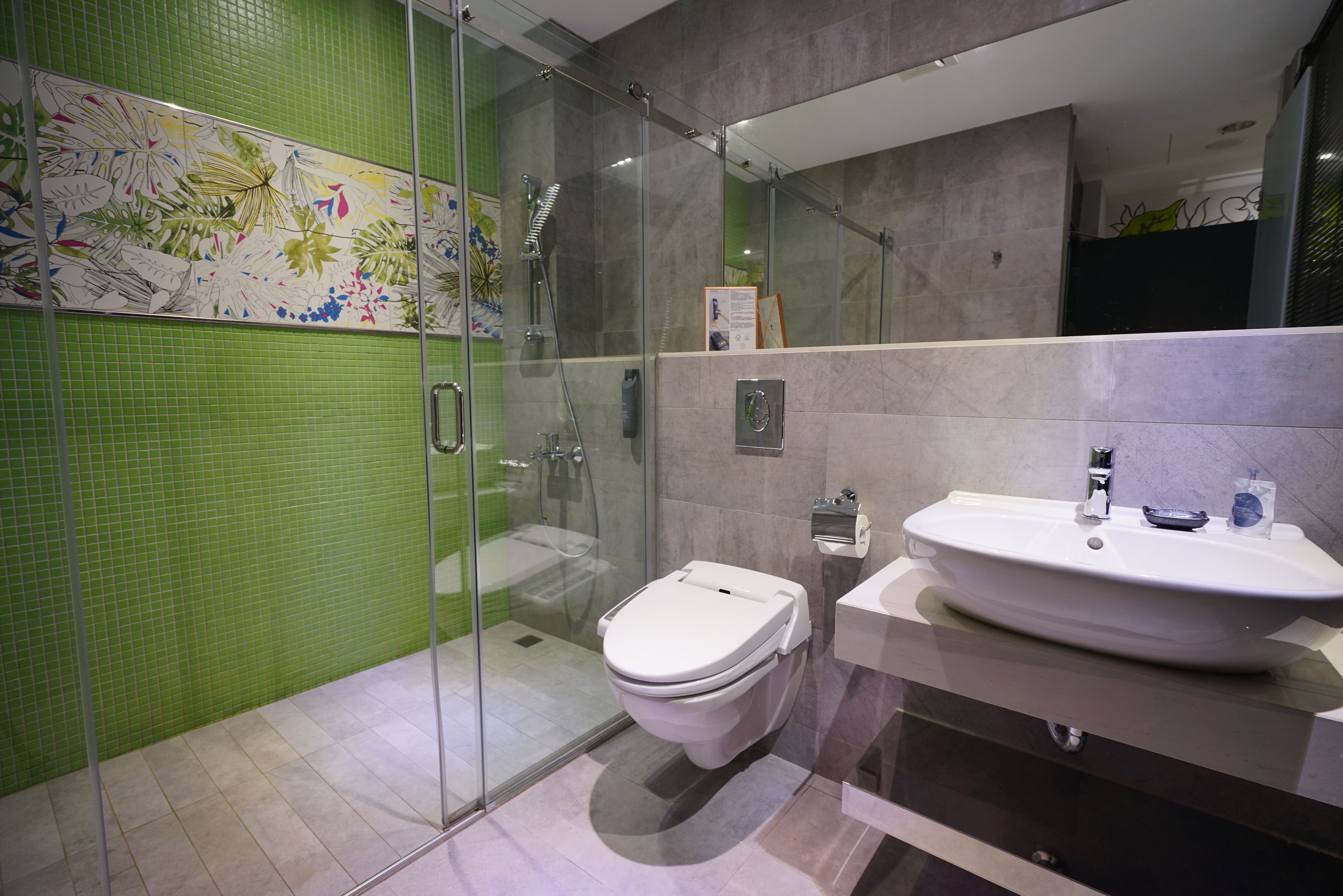 Un baño moderno con cabina de ducha de vidrio, inodoro y lavamanos con espejo.
