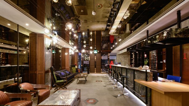 A modern hotel lobby with leather seating, a reception desk, and a bar area. - 3 Door Hotel (Tainan)
