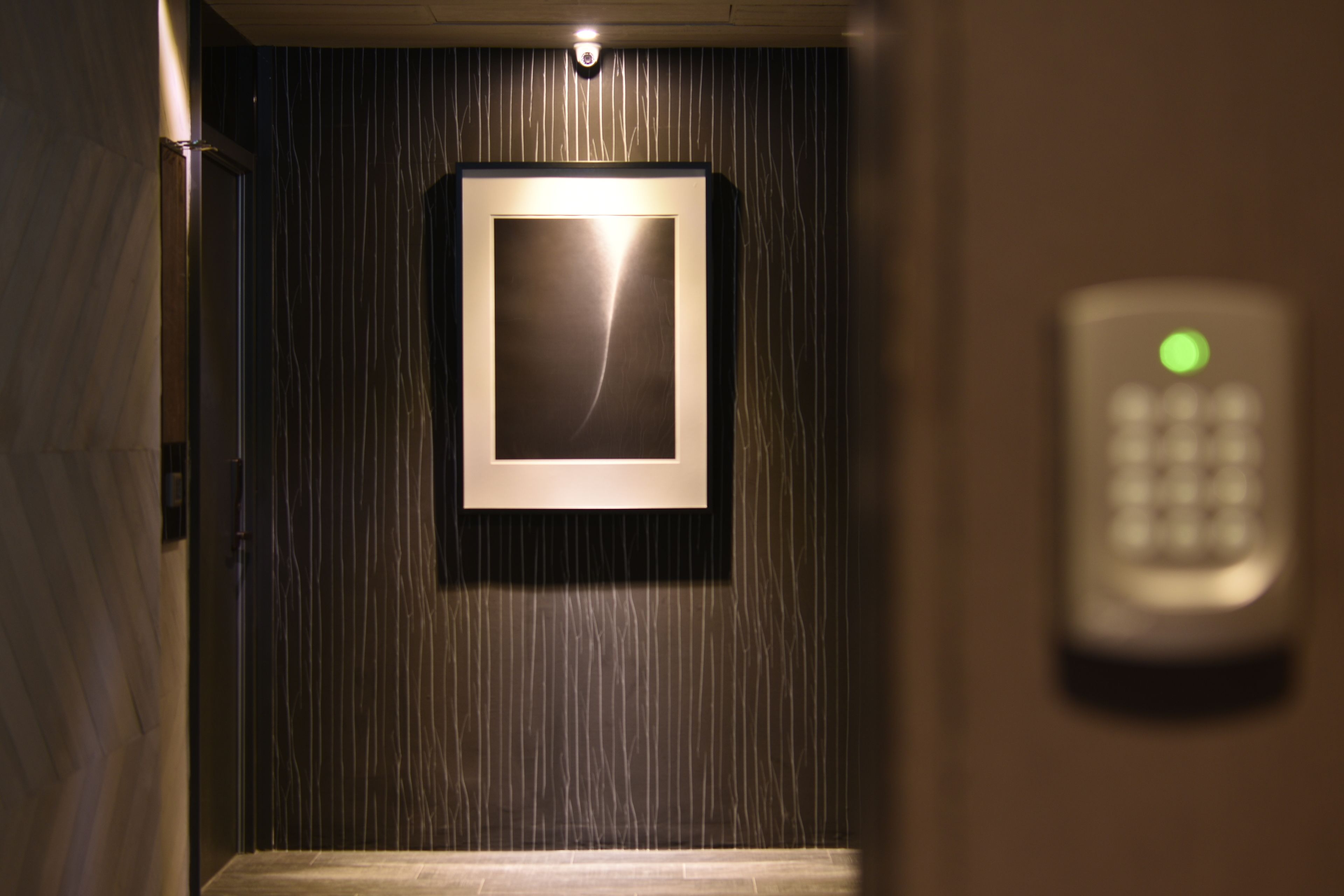 An elevator interior with a wall-mounted light fixture and a keypad control panel.