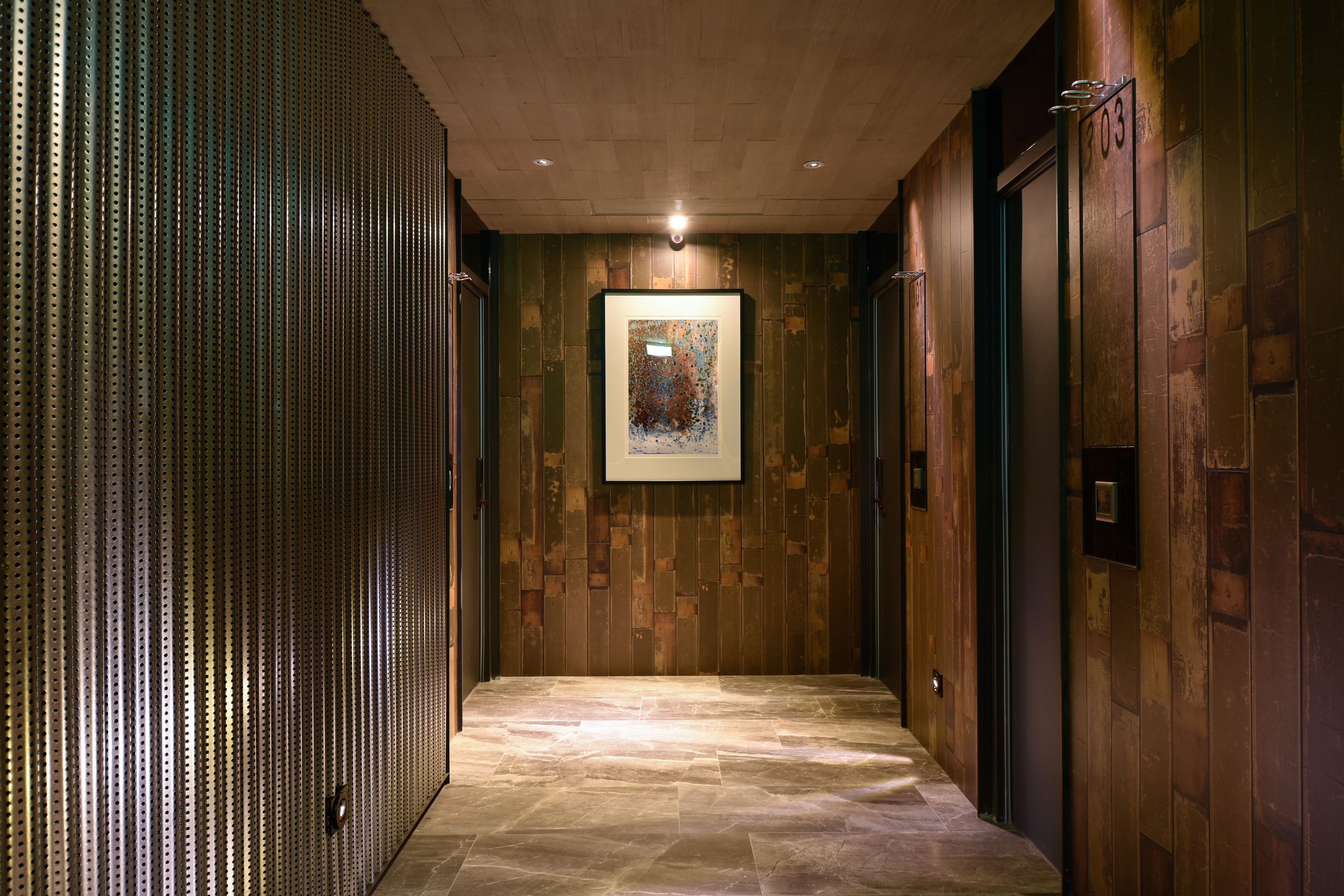 A hallway with a stone floor, wooden walls, and a framed artwork on the wall.