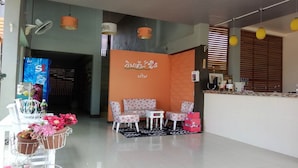 A hotel lobby with a reception desk, seating area, and a wall with a floral design. - Winhouse Hotel (Nan)