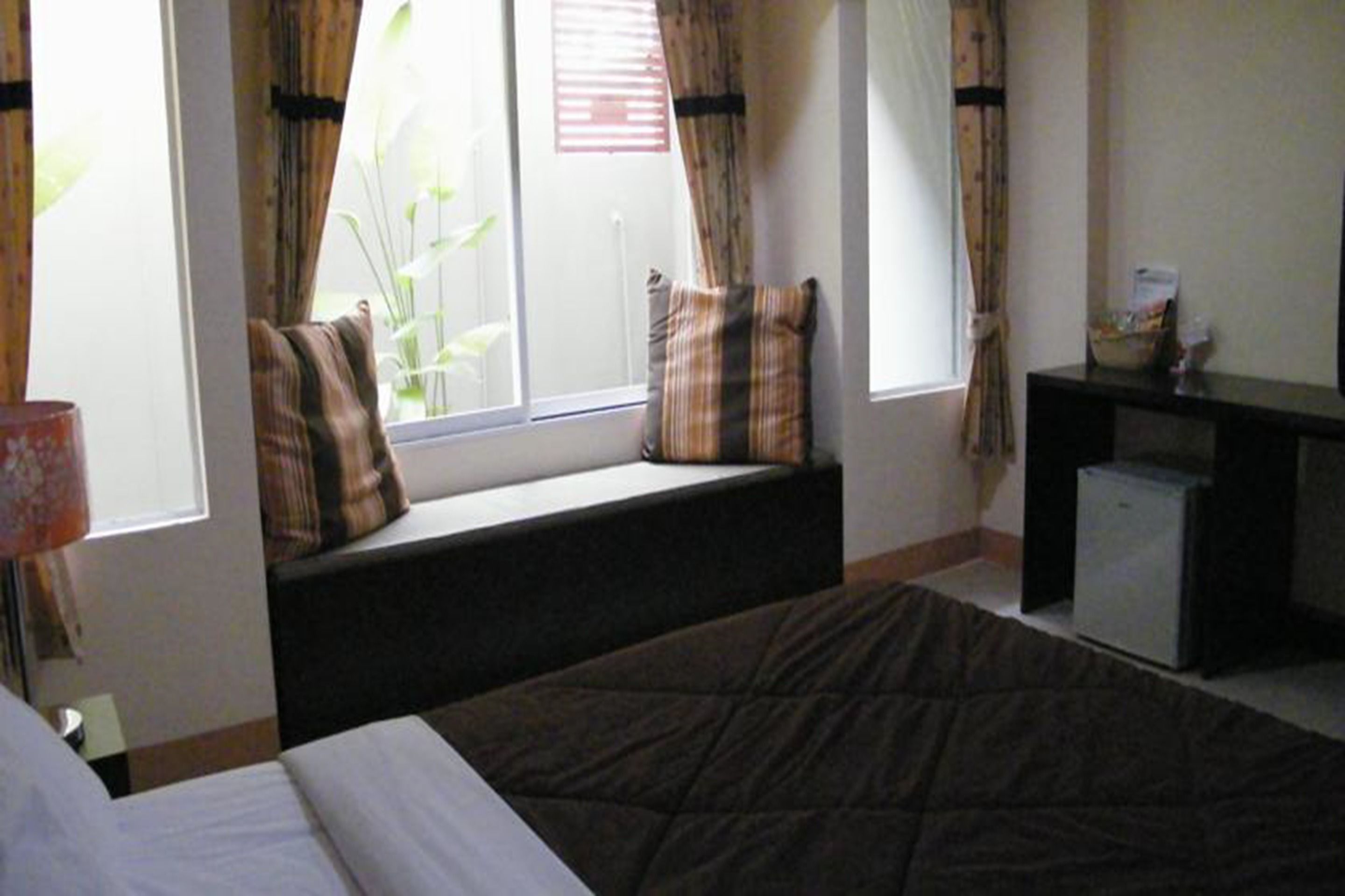 A bedroom with a bed, a bench by the window, and a small desk.