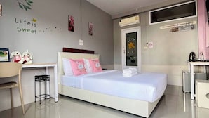 A modern bedroom with a bed, a desk, and a chair. There is a wall decoration with the text "Life is Sweet" and a small window above the bed. - Winhouse Hotel (Nan)