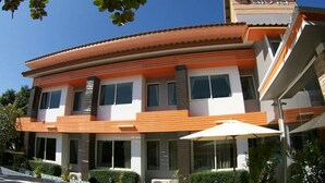 A modern two-story building with a curved roofline, large windows, and a white umbrella. - Winhouse Hotel (Nan)