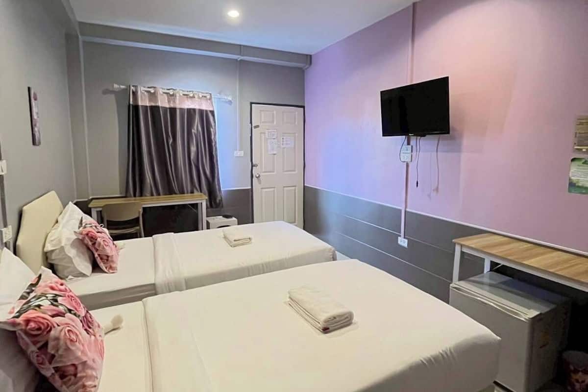 A hotel room with two beds, a desk, a TV, and a shower area.