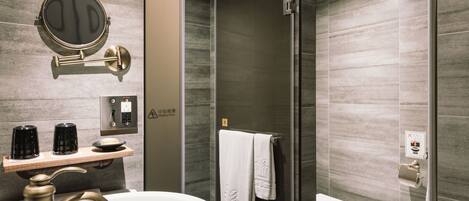 A modern bathroom with a round mirror, a sink, a glass shower enclosure, and a toilet.
