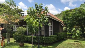 A house with a tiled roof, surrounded by lush greenery and a giraffe statue. - Chanpraya Resort (Chanthaburi)