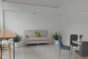 A room with a sofa, two chairs, a small table, and potted plants. - Nornnan Hotel (Nan)