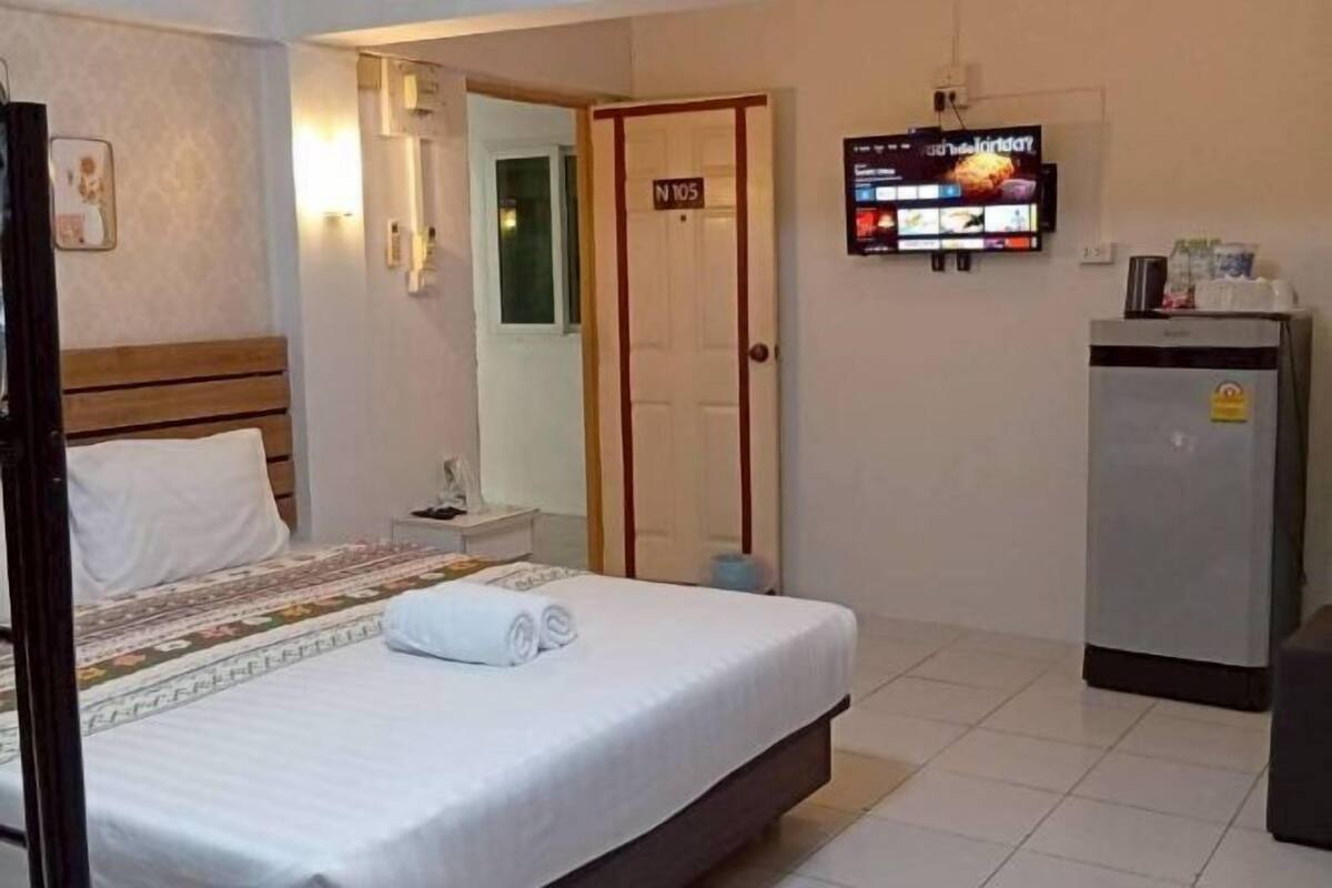 A hotel room with a bed, a television mounted on the wall, a refrigerator, and a door marked "N105".